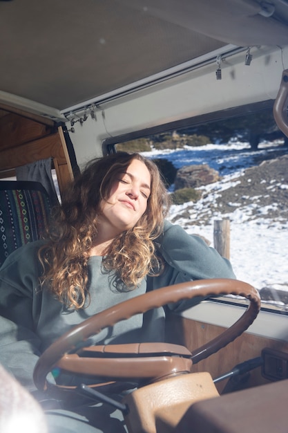 Mujer joven durmiendo en una autocaravana durante el invierno