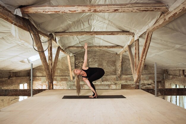 Mujer joven ejercicios de yoga en un sitio de construcción abandonado