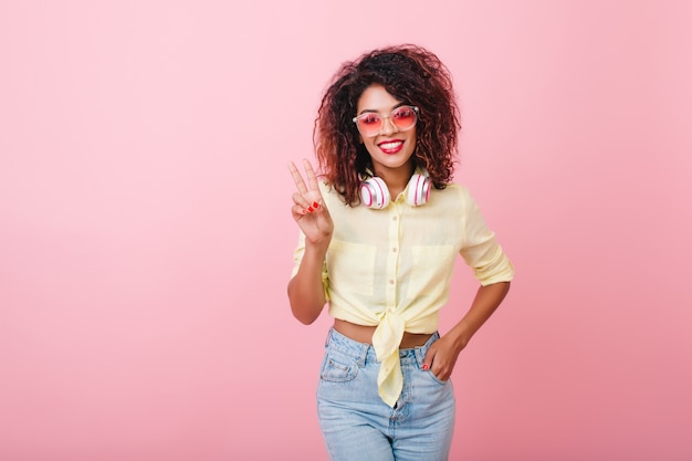 Mujer joven elegante de buen humor posando con ropa nueva. hermosa chica adorable con peinado africano.