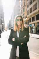 Foto gratuita mujer joven elegante feliz con las gafas de sol en la calle en día soleado