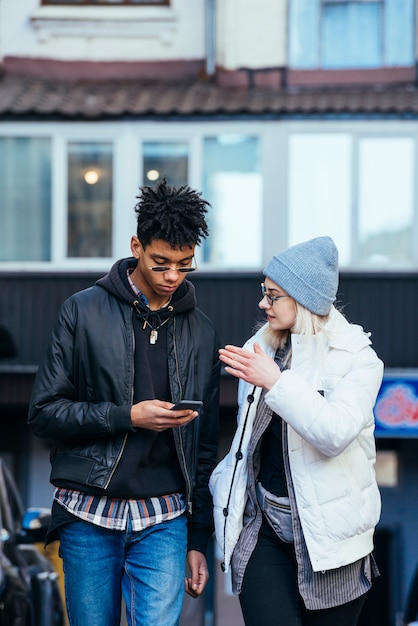 Mujer joven elegante que habla con su novio hermoso que usa el teléfono móvil