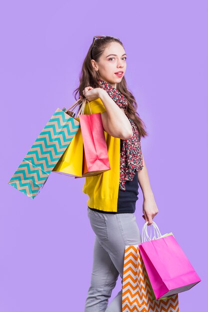 Mujer joven elegante que lleva la bolsa de papel colorida