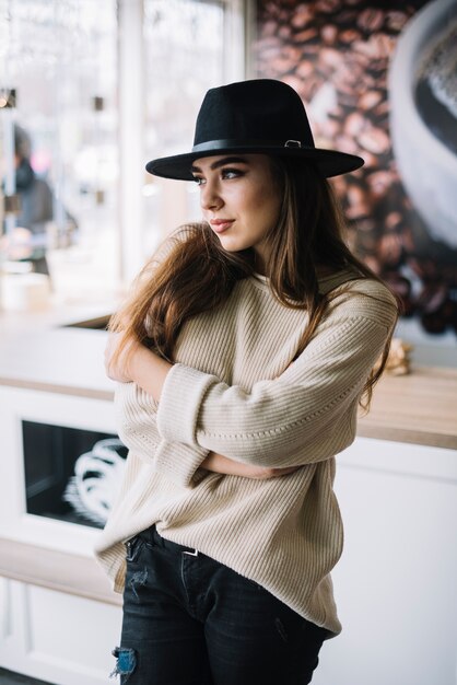 Mujer joven elegante en sombrero con las manos cruzadas