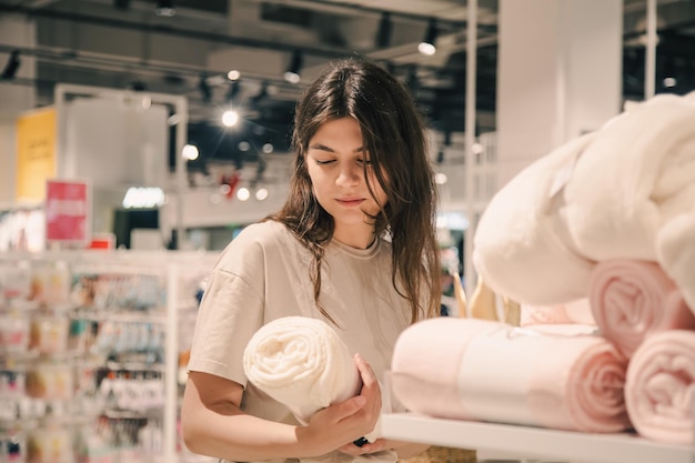 Foto gratuita una mujer joven elige mantas para el interior de una casa en una tienda de mejoras para el hogar