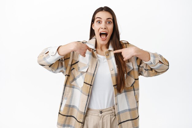 Mujer joven emocionada apuntando a sí misma