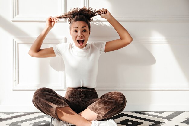 Mujer joven emocionada jugando con el pelo rizado