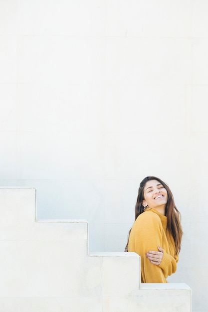 Foto gratuita mujer joven emocionada de pie contra la pared blanca