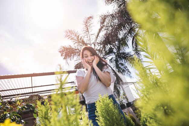 Mujer joven emocionada que mira la planta en invernadero