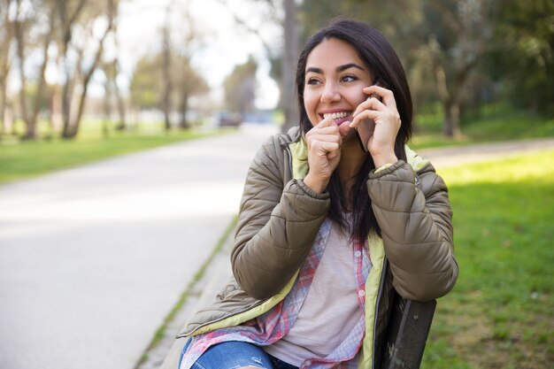 Mujer joven emocionada que ríe mientras que habla en el teléfono