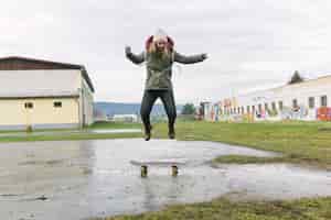 Foto gratuita mujer joven emocionada que salta sobre el monopatín