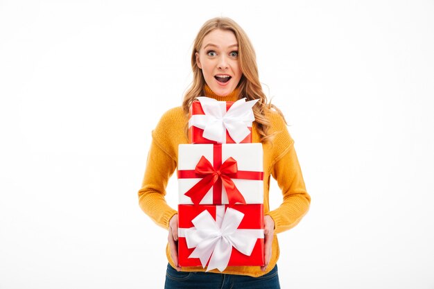 Mujer joven emocionada que sostiene las cajas de regalo de la sorpresa.