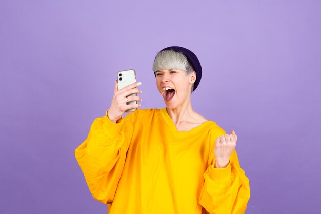 Mujer joven emocionada sorprendida por el increíble mensaje de venta de la aplicación móvil de compras mirando el teléfono inteligente, chica ganadora sosteniendo el teléfono celular gritando de alegría