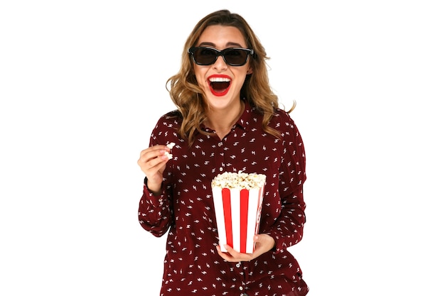 Mujer joven emocional con palomitas viendo la película de éxito en vidrios estéreo