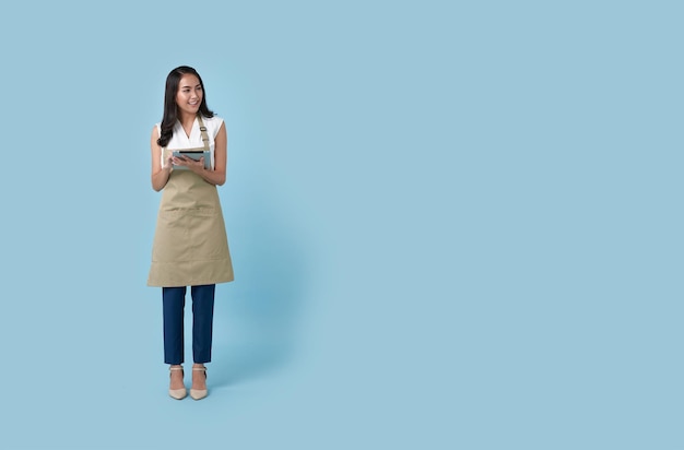 Mujer joven empresaria asiática en delantal mano sosteniendo tableta para comida de pedido de lista