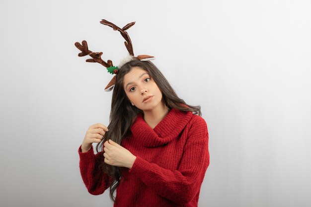 Una mujer joven se encuentra con una diadema en forma de cuernos navideños.