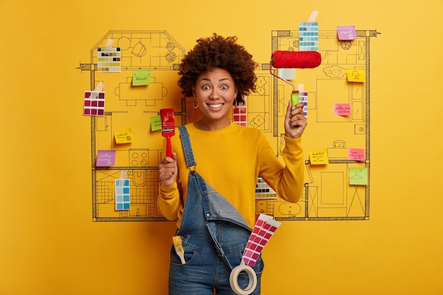 Mujer joven se encuentra junto al boceto de diseño de la casa listo para la renovación