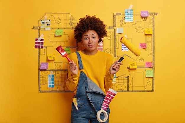 Mujer joven se encuentra junto al boceto de diseño de la casa listo para la renovación