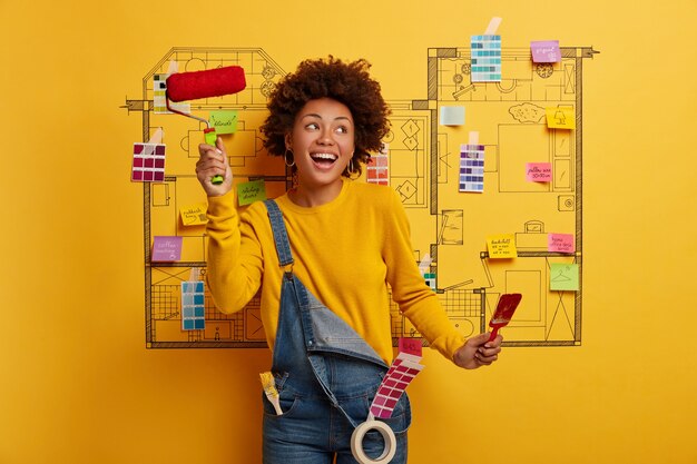 Mujer joven se encuentra junto al boceto de diseño de la casa listo para la renovación