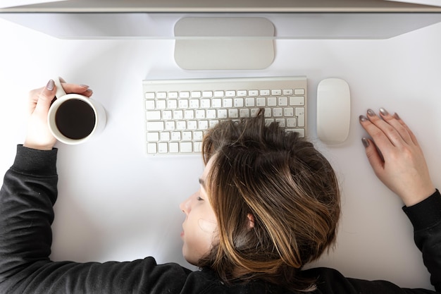 Mujer joven endecha plana dormida frente a una computadora