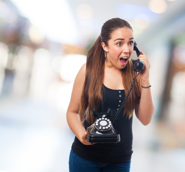 Mujer joven enfadada usando un teléfono clásico