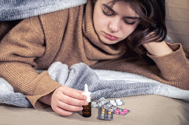 Mujer joven enferma con medicamentos se encuentra en cama resfriados y tratamiento en el hogar