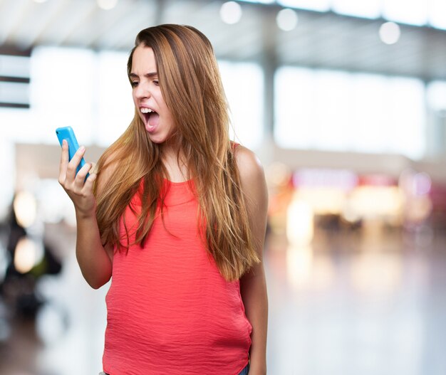 mujer joven enojado gritando a móvil en el fondo blanco