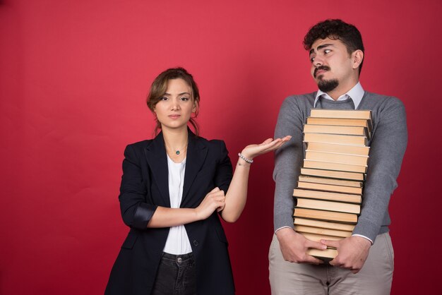 Mujer joven enojarse con el hombre que lleva un montón de libros