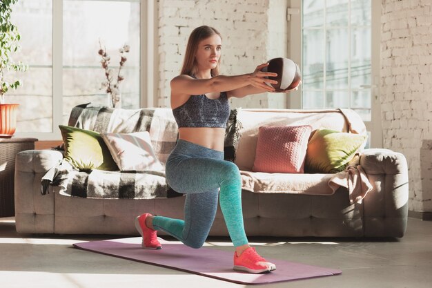 Mujer joven enseñando en casa cursos en línea de fitness estilo de vida deportivo aeróbico mientras está en cuarentena