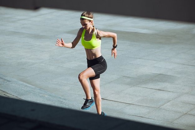 Mujer joven entrenando al aire libre bajo el sol de otoño. Concepto de deporte, estilo de vida saludable,