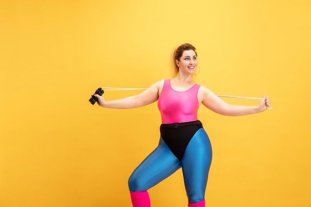 Mujer joven entrenando en pared amarilla