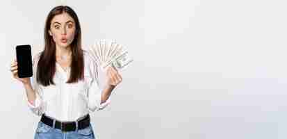 Foto gratuita mujer joven entusiasta que gana dinero mostrando la interfaz de la aplicación de teléfono inteligente y el premio de microcrédito en efectivo c