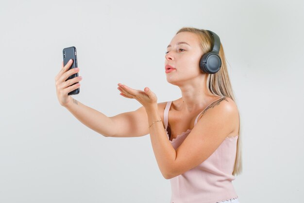 Mujer joven enviando beso en videollamada en camiseta