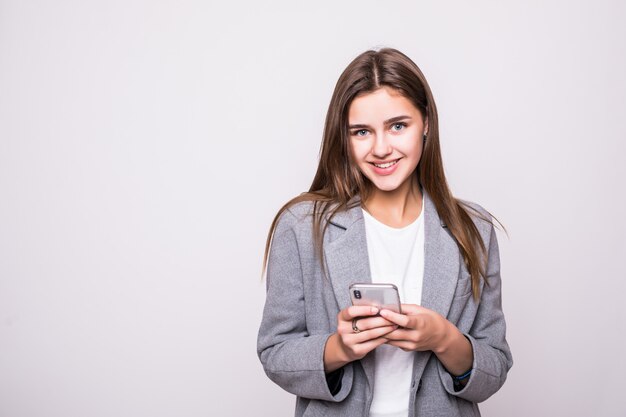 Mujer joven enviando un sms por teléfono celular, aislado sobre fondo blanco.