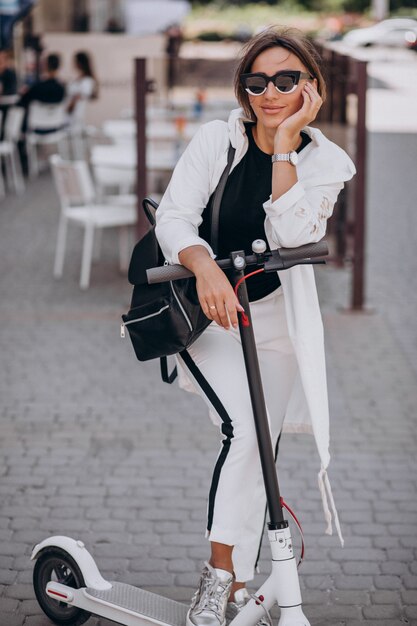 Mujer joven, equitación, patineta, en la calle