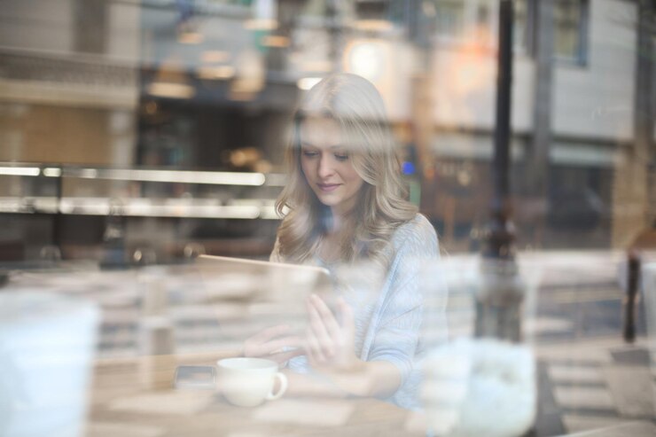 mujer joven escribe con una tableta en un café