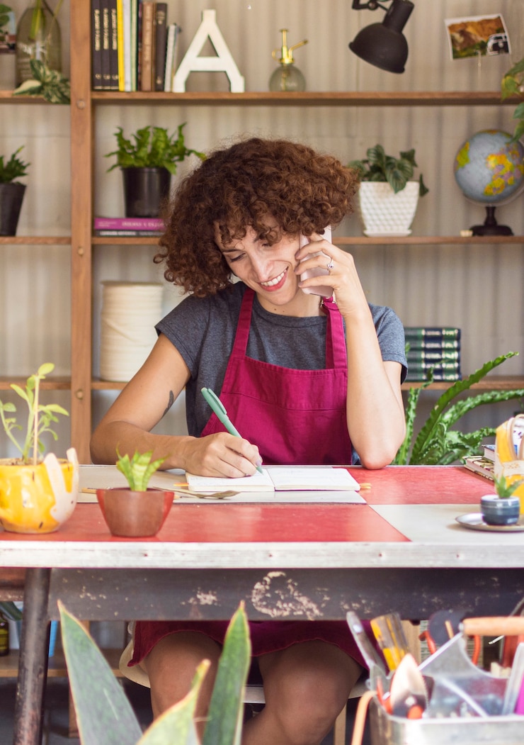 Foto gratuito mujer joven escribiendo algo en su cuaderno en invernadero