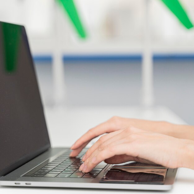 Mujer joven escribiendo en un teclado de computadora portátil