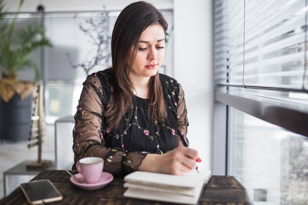 Mujer joven, escritura, en, diario, en, restaurante