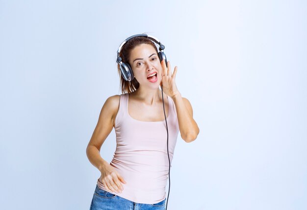 Mujer joven escuchando auriculares y susurrando