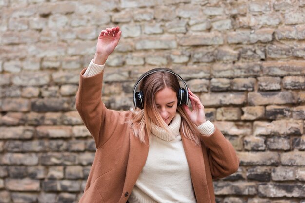 Mujer joven escuchando música con auriculares afuera