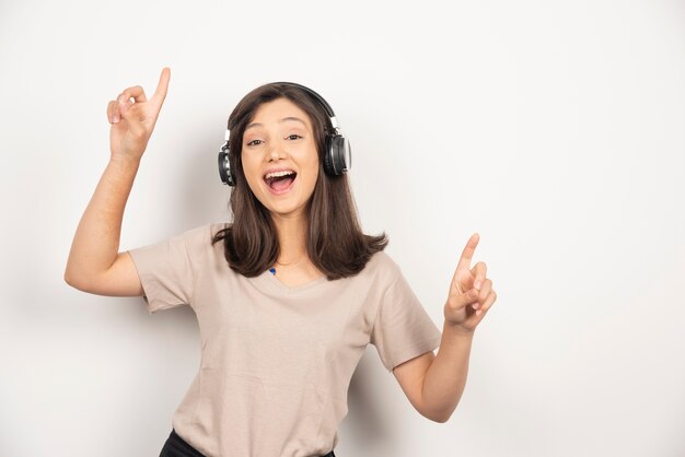 Mujer joven escuchando música en auriculares y bailando.