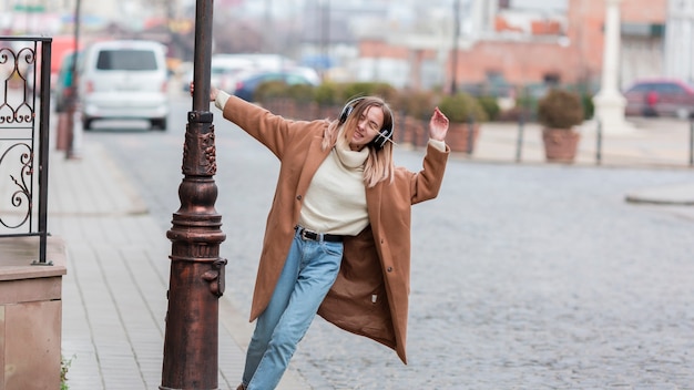 Mujer joven escuchando música con auriculares en la ciudad