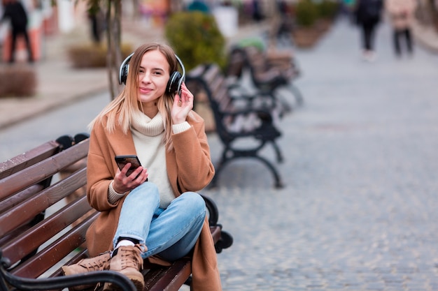 Mujer joven escuchando música en auriculares con espacio de copia