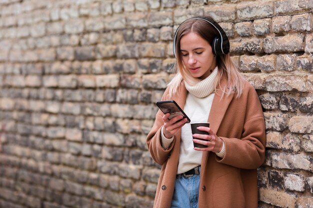 Mujer joven escuchando música en auriculares con espacio de copia