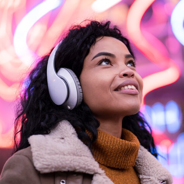 Mujer joven escuchando música en auriculares fuera