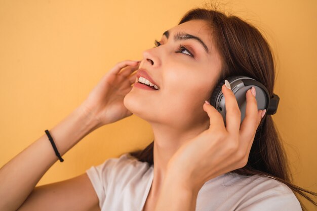 Mujer joven escuchando música con auriculares.