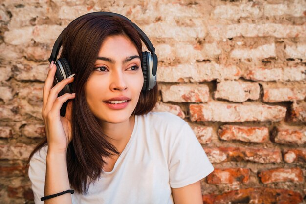 Mujer joven escuchando música con auriculares.