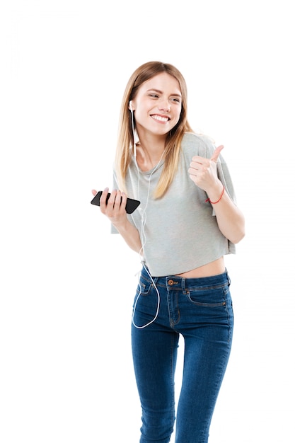 Mujer joven escuchando música y mostrando el pulgar hacia arriba