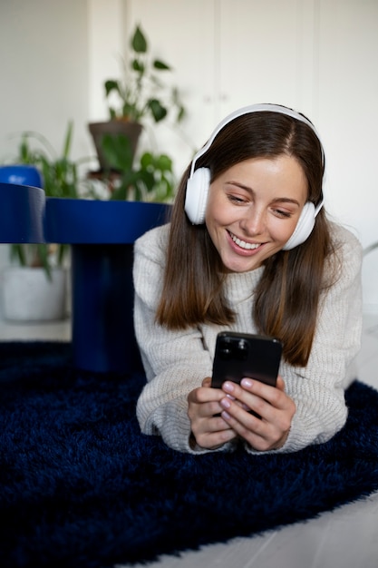 Mujer joven escuchando música con su teléfono inteligente y sonriendo