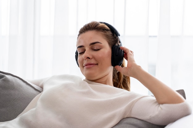 Foto gratuita mujer joven escuchando música a través de sus auriculares